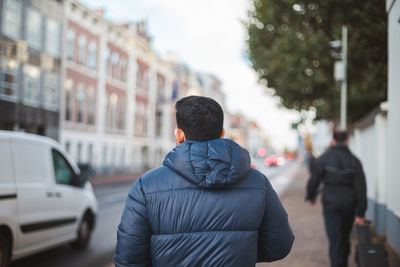 Rear view of people walking on street in city