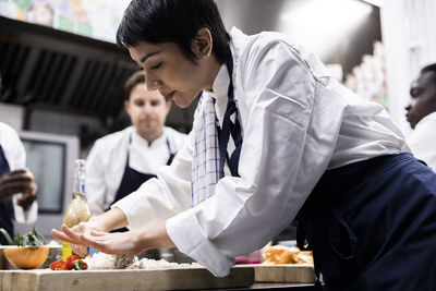 Side view of female chef cutting onion while working in commercial kitchen