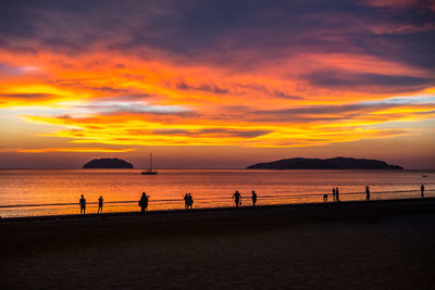 Silhouette people on beach against sky during sunset