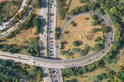 Cars drive along a loop shaped road junction top view.