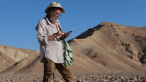 Senior man using mobile phone in the desert 