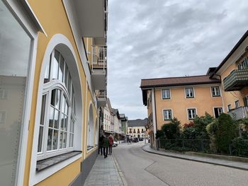 People on street amidst buildings in city against sky