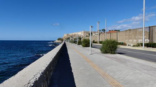 Road by sea against blue sky
