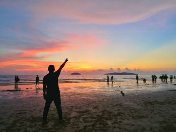 Silhouette people at beach against sky during sunset