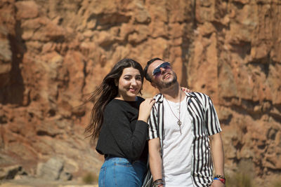 Portrait of smiling young couple standing against mountain