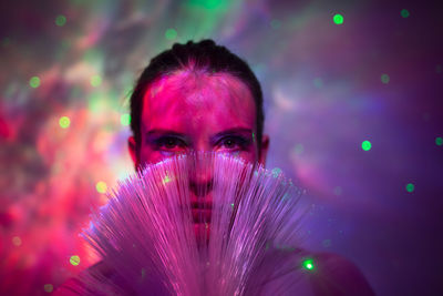 Close-up portrait of woman against pink background