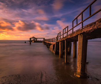 Pier over sea against sky during sunset