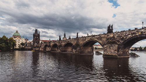 Arch bridge over river against cloudy sky