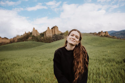 Young woman standing on field against sky