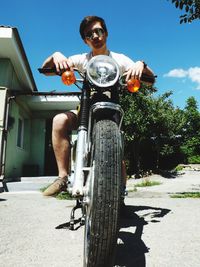 Low angle view of man sitting on motorcycle during summer