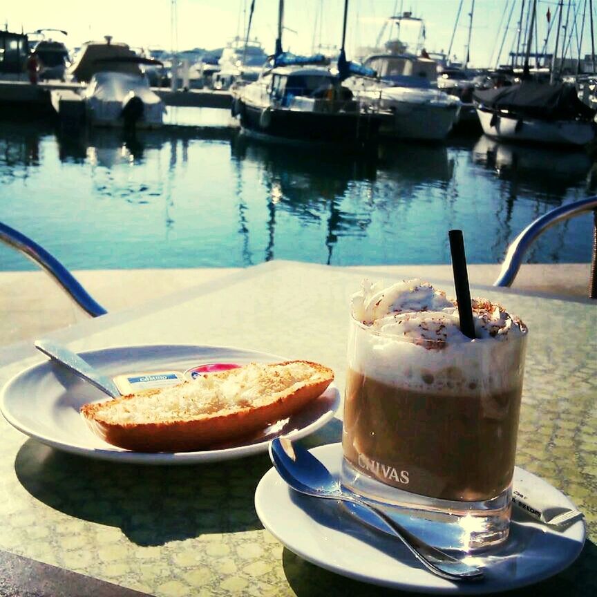 food and drink, nautical vessel, water, moored, table, boat, refreshment, transportation, drink, freshness, mode of transport, food, harbor, plate, restaurant, outdoors, day, serving size, sunlight, reflection