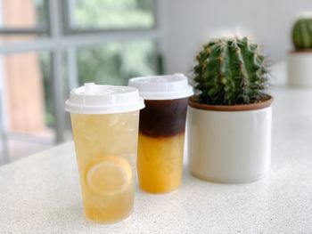 Close-up of lemon tea and orange coffee in glass on table