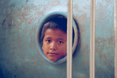 Portrait of boy peeking through metal