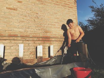 Full length of shirtless man standing against wall