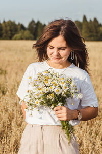 Beautiful woman standing by flower plant on field