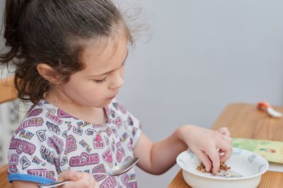 Cute young girl is playing with her food and making faces