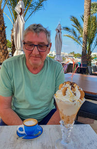 Man sits at table with ice cream cup and espresso in blue cup