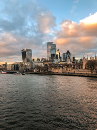 River by buildings against sky during sunset