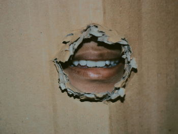 Man lips seen through torn cardboard