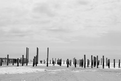 Wooden posts on beach against sky