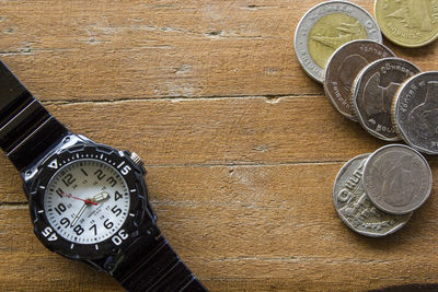 High angle view of wristwatch and coins on table