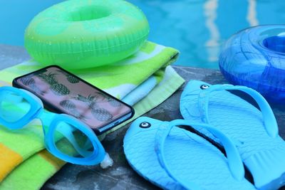 Close-up of flip-flops with towel at poolside