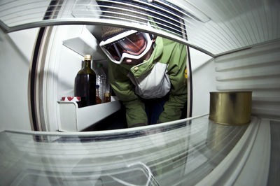 Man in protective suit inspecting refrigerator