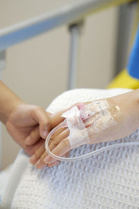 Close-up of kid holding the hand of a mother at the hospital