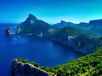 Scenic view of sea and mountains against blue sky