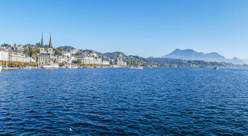 Sea by buildings against clear blue sky