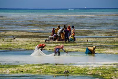 People at beach against sky