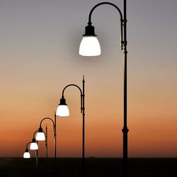 Illuminated street lights against clear sky during sunset