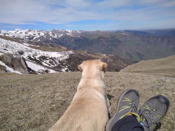 Low section of man standing on mountain against sky