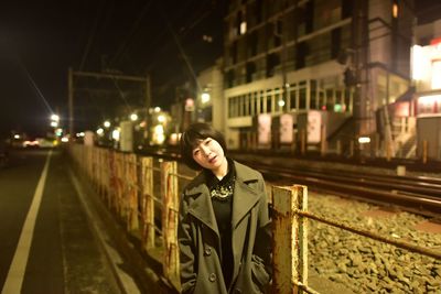 Young woman standing on railroad track at night