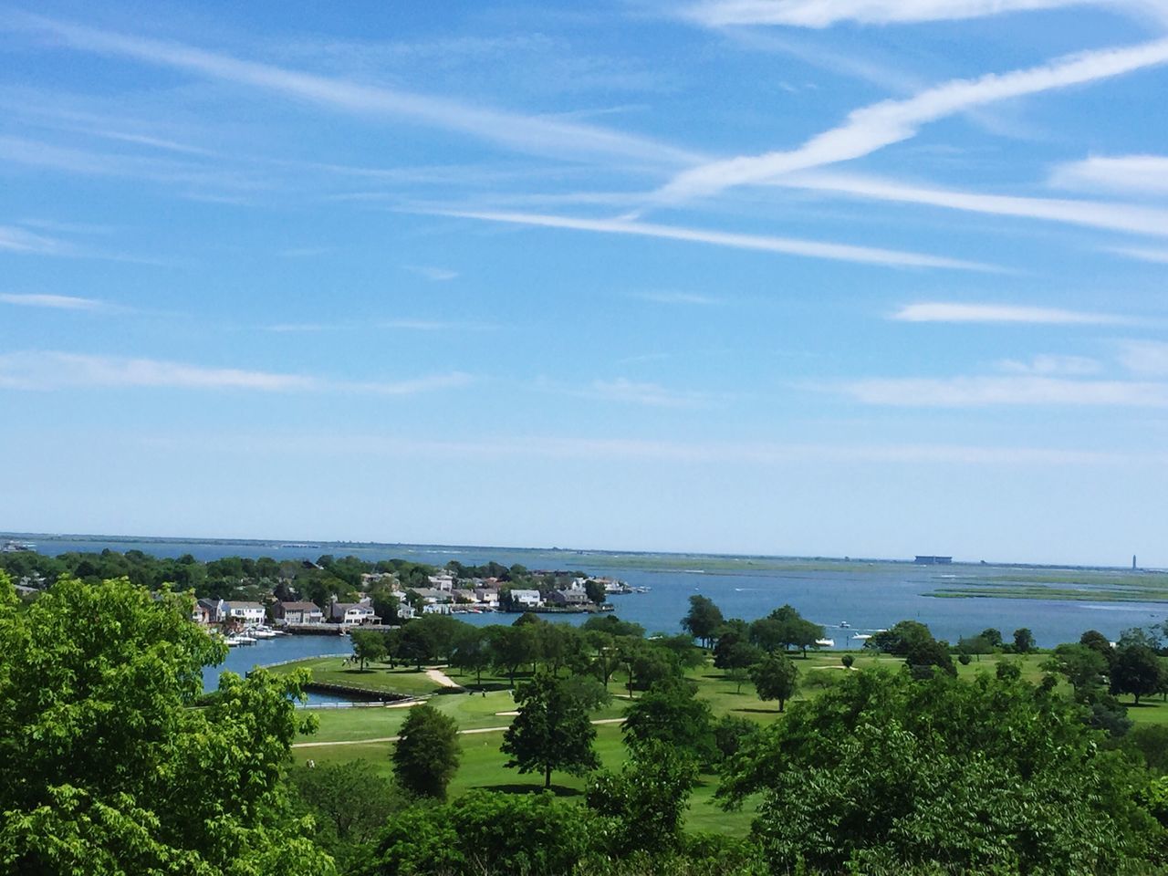 Wispy clouds and blue skies with a view of the water