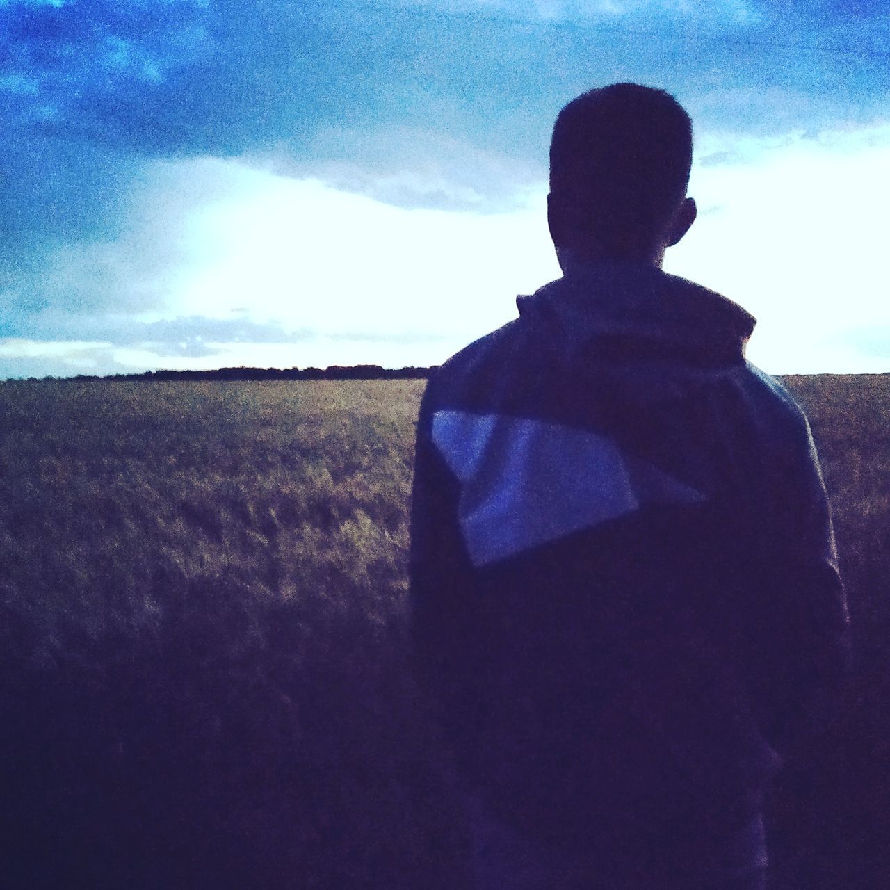 REAR VIEW OF MAN LOOKING AT SUNSET