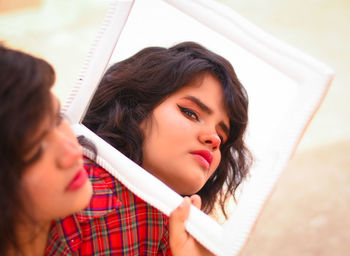 High angle view of woman holding mirror with reflection