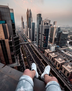 Low section of man and buildings in city against sky