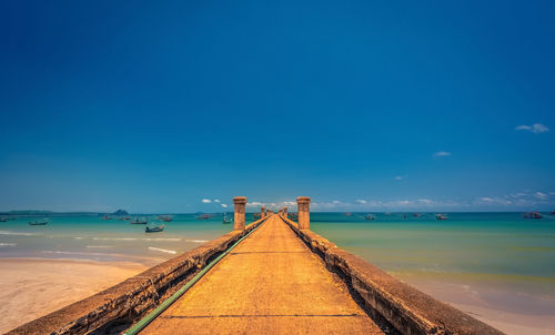 Jetty bridge on to the sea in blue summer sky for boat and ship.