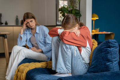 Side view of young woman sitting on bed at home