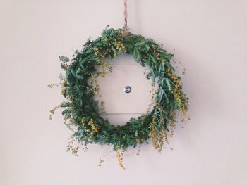 Close-up of wreath and peephole on white door