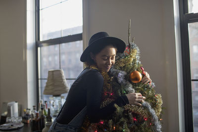 A young woman hugging a christmas tree