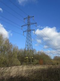 Low angle view of electricity pylon on field against sky