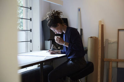 Side view of confident female architect working at table in office