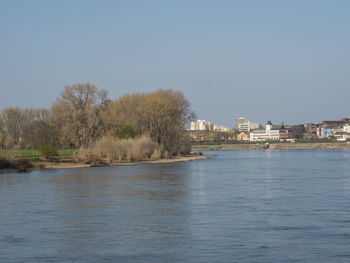 Scenic view of river by buildings against clear sky