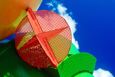 Low angle view of colorful metallic built structure against blue sky