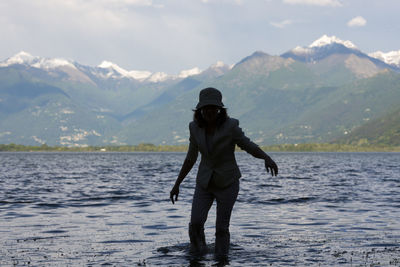 Woman standing in lake maggiore against mountains