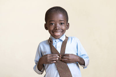 Portrait of smiling boy standing against white background