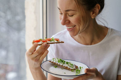 Close-up of woman eating food while looking out of window