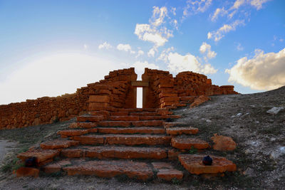 Low angle view of old ruin building against cloudy sky